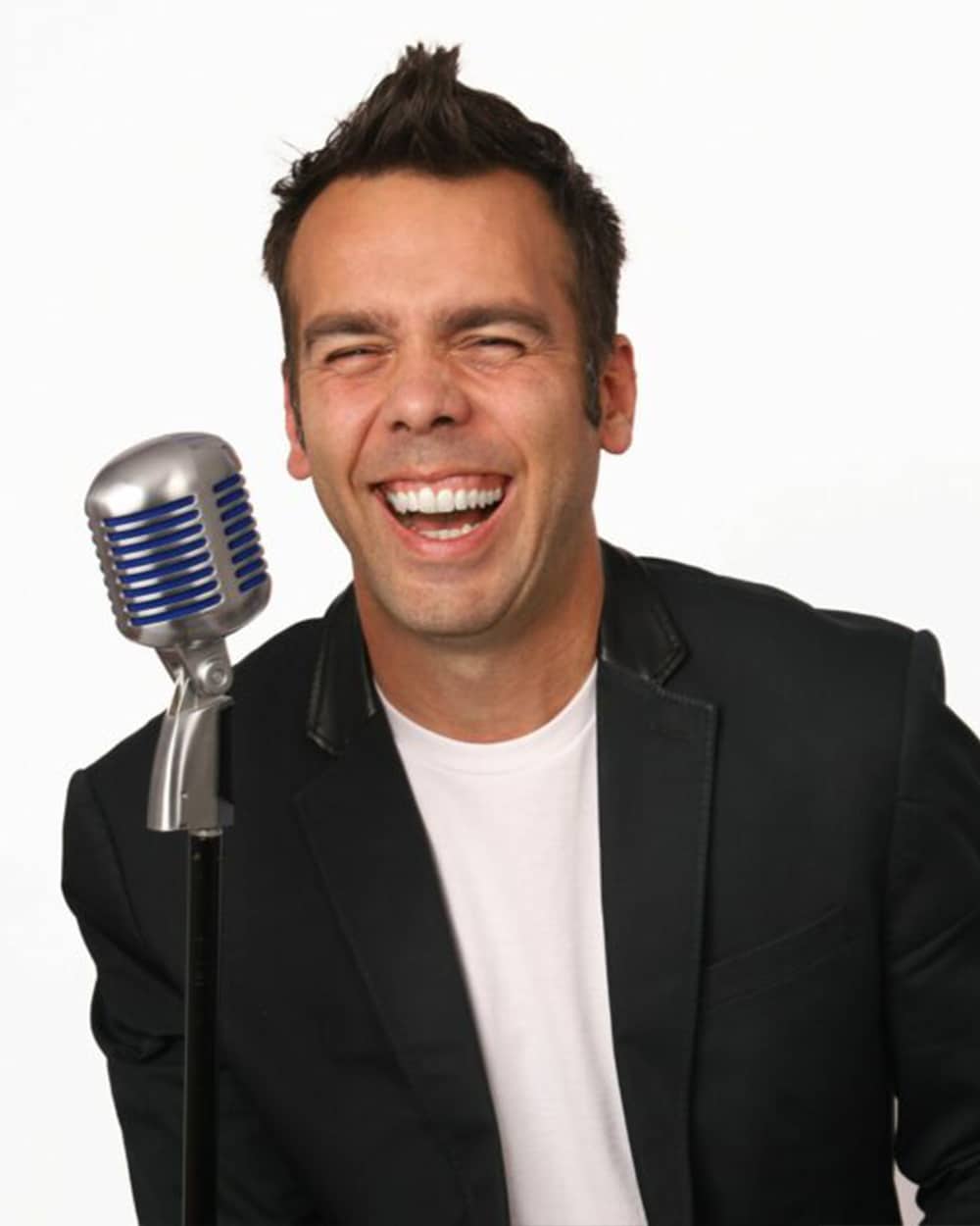 A person laughing while holding a retro microphone against a white background.
