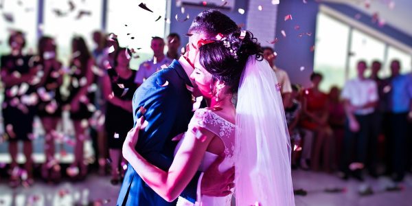 Bride and groom dancing together amidst falling confetti at their wedding.